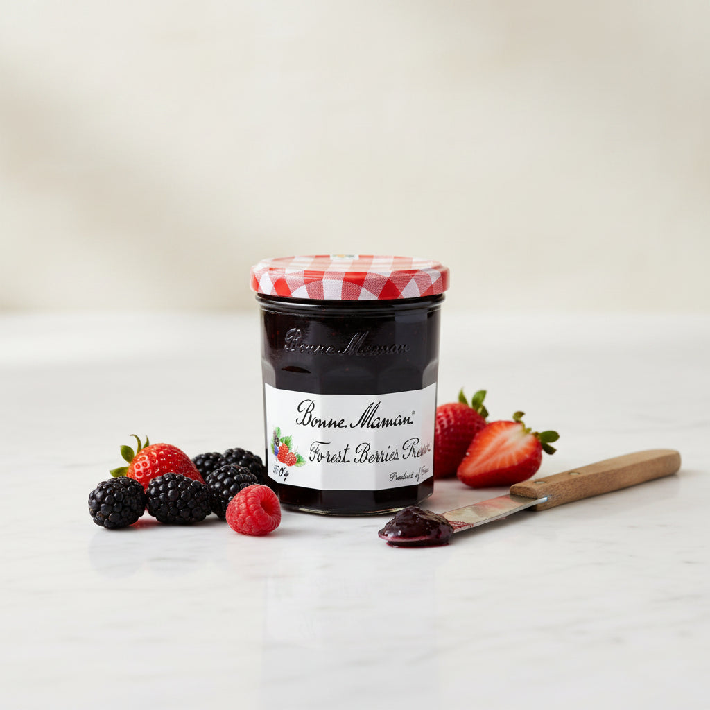 A glass jar of Bonne Maman Forest Berries Preserve with a red and white checkered lid, set against a plain off-white background.