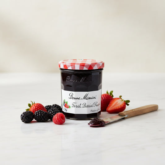 A glass jar of Bonne Maman Forest Berries Preserve with a red and white checkered lid, set against a plain off-white background.